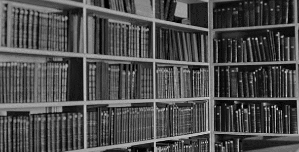 Shelves in a library containing many books